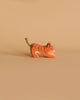 A small handcrafted wooden figurine of an orange tiger with black stripes and a rope tail, named Ostheimer Tiger Lurking, Small, is placed against a beige background. The toy appears to be in a crouching or playful position, perfect for imaginative play.