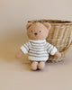 Sentence with product name: A small, plush Teddy Bear in a polyester cotton white and gray striped sweater, sitting in front of a woven basket on a light beige background.