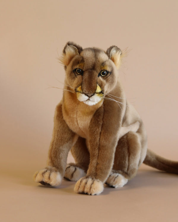 A realistic plush model of a Mountain Lion Stuffed Animal sitting against a plain background, featuring detailed fur, whiskers, and striking eyes, bringing out its unique personality.