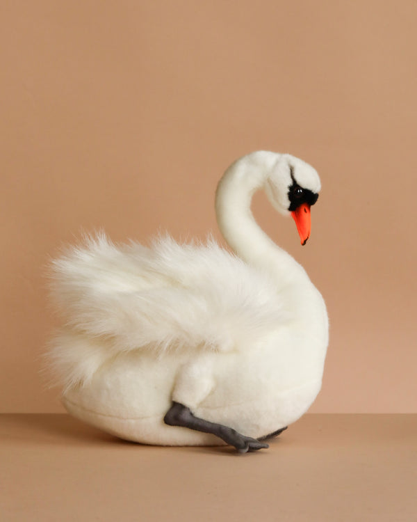 The White Swan Bird Stuffed Animal by HANSA Animals features lifelike detail with white plush feathers, an orange beak, and black face accents. Each hand-sewn piece is crafted for realism and shown against a plain beige background.