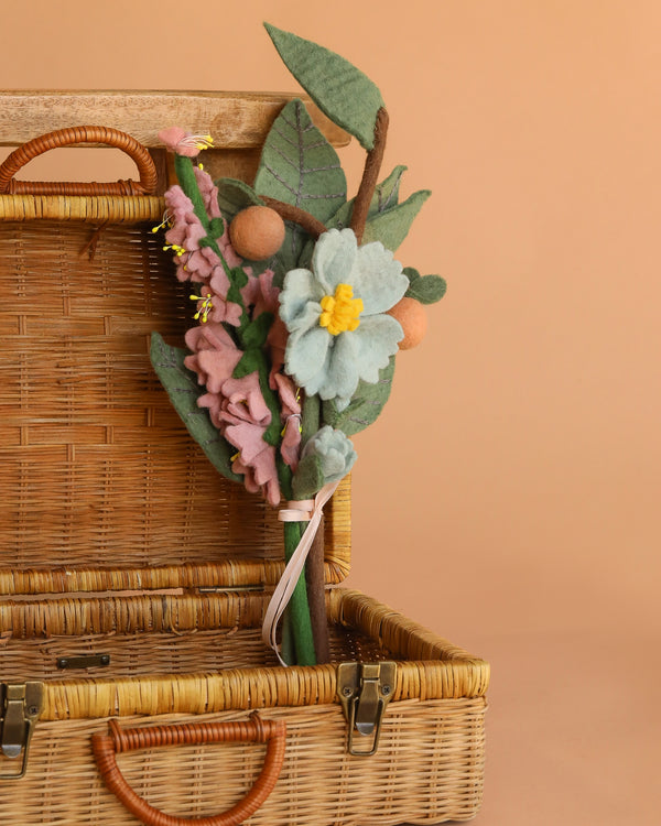 The Handcrafted Felt Flower Bouquet, featuring sustainable pastel felt blooms, is arranged in an open wicker basket set against a warm beige background.