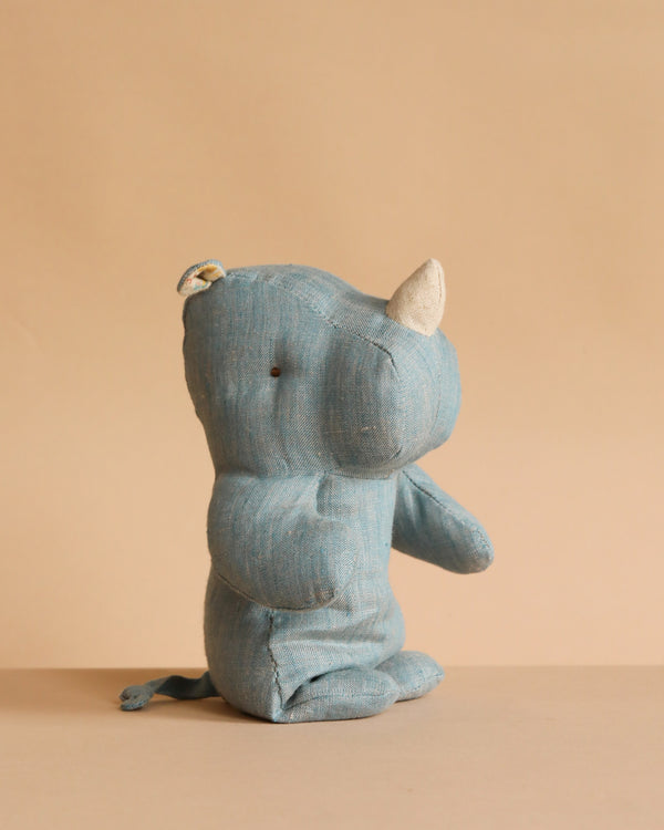 The Maileg Small Rhino - Blue Sand, crafted from the softest fabric and filled with recycled polyester, sits on a beige surface with a matching background, facing right.