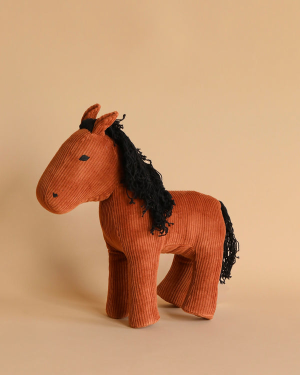 A Fabelab Friends Stuffed Animal named Horse Hector, crafted with sustainable textured corduroy fabric in a warm brown color, featuring stitched eyes and a black mane and tail, presented against a soft beige background.