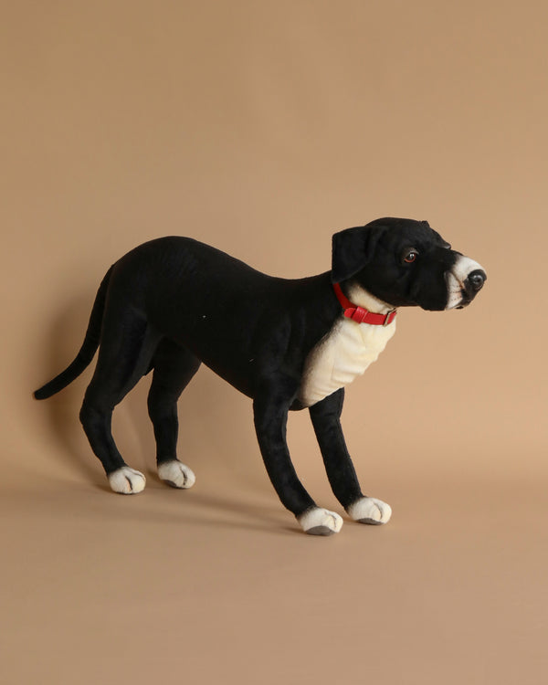 A lifelike Great Dane stuffed animal, crafted by HANSA animals, standing against a solid beige background.
