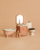 The Maileg Bathroom Set includes a bathtub, vanity with mirror, sink, toothbrush, soap, stool with bottles, and toilet in soft pink and white—ideal for displaying Maileg mouse furniture against a beige background.