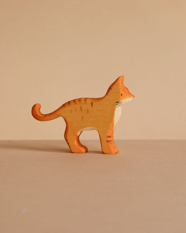 The Handmade Wooden Ginger Cat is a small figurine crafted from sustainable hardwood, depicting a ginger tabby with darker stripes. It stands on a beige surface against a matching background.