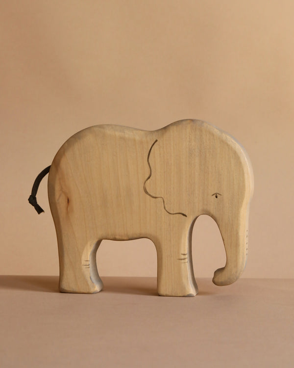 The Handmade Wooden Elephant is a sustainable hardwood toy featuring simple carved details and a small black tail, displayed on a plain beige background.