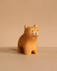 The Bumbu Handmade Wooden Bear and Forest Trees Set features a small, light brown bear figurine crafted from sustainably sourced wood, with simple painted details that invite sensory exploration against a neutral beige background.