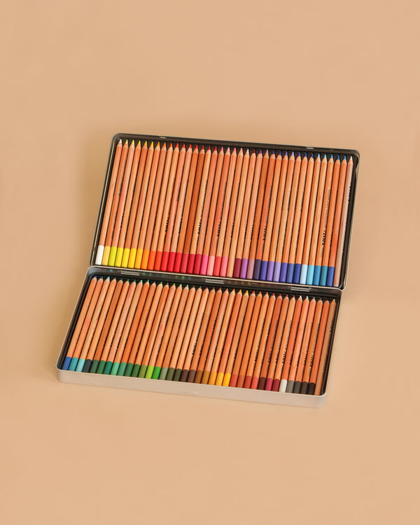 A metal tin holding 72 assorted Lyra Rembrandt Polycolor oil-based colored pencils, arranged in two rows with colored tips, showcases a vibrant color range against a light brown background.