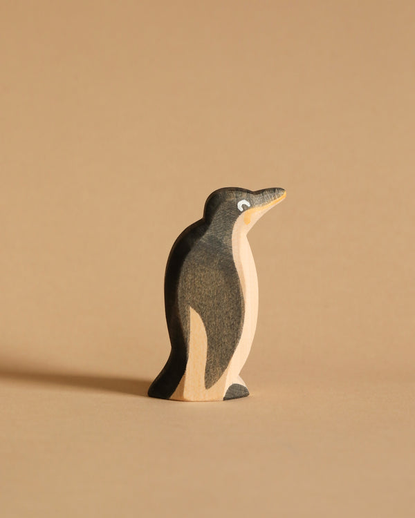 An Ostheimer Penguin - Head High figurine stands against a plain beige background. The small, handcrafted wooden penguin is painted in black and white with a simplistic and smooth design, featuring a small eye painted on its head. This charming piece exemplifies sustainable materials used in artisan craftsmanship.