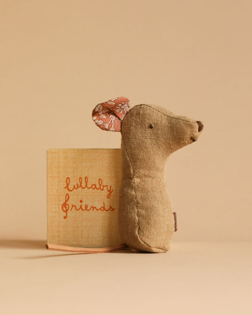 The Newborn Gift Set - Blue, featuring a small beige fabric mouse with floral ears, a "lullaby friends" book, and Grimm's Small Wooden Rainbow, is displayed on a neutral beige background.
