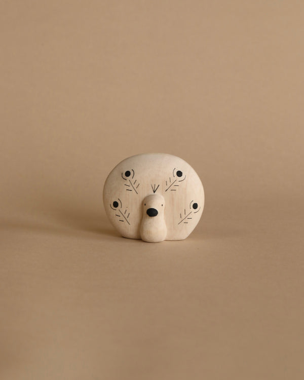 A whimsical handcrafted wooden sculpture of a stylized face with multiple simple eyes and a central nose, set against a plain beige background.