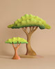 Two cartoonish trees with green foliage, one larger with a brown trunk and the other smaller with an orange trunk, placed against a beige background. The whimsical, hand-painted appearance of these Bumbu Wooden Acacia Tree Set creations evokes a sense of playful charm.