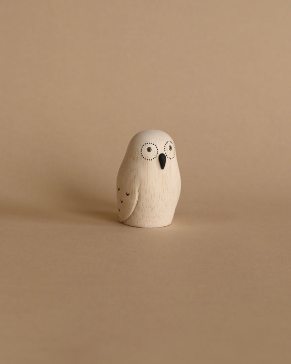 A small, Handmade Tiny Wooden Exotic Animals - Owl figurine handcrafted from Albizia wood with a simplistic, round design and two big, circular eyes on a plain beige background.