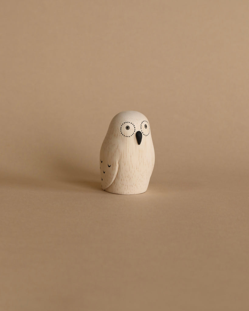 A small, Handmade Tiny Wooden Exotic Animals - Owl figurine handcrafted from Albizia wood with a simplistic, round design and two big, circular eyes on a plain beige background.