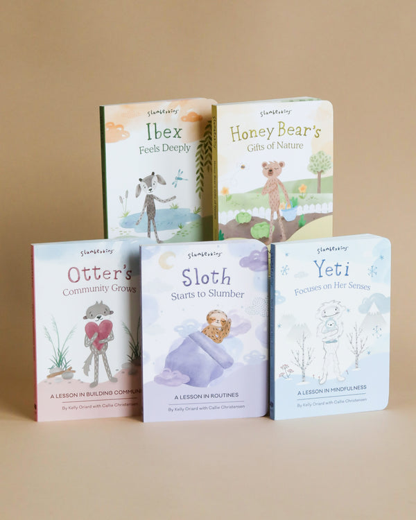 Five colorful children's books from the "Slumberkins A Lesson in Caring Board Book Set", each featuring a different animal character and a lesson in caring, displayed upright against a plain beige background.