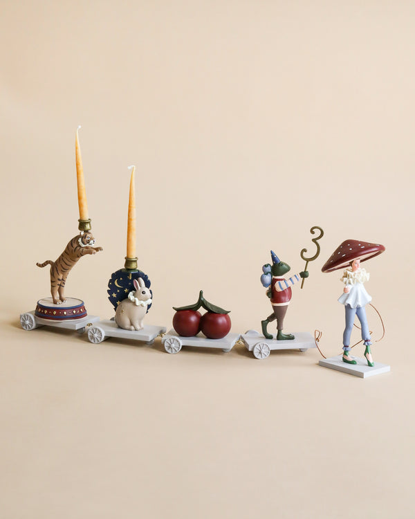 The Magical Forest Birthday Train With Beeswax Candles features four connected carts—a tiger with candles, a rabbit, cherries, a mouse with party hat and stick, and a mushroom-capped figure—perfect for your birthday celebration.