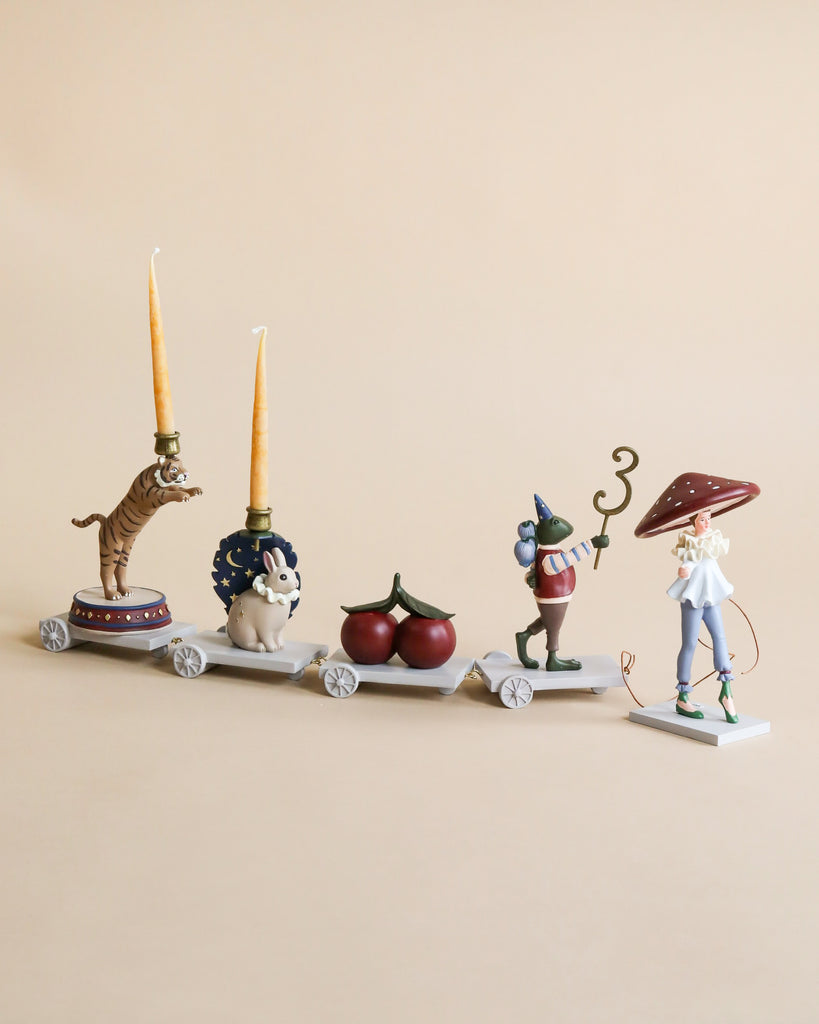 The Magical Forest Birthday Train With Beeswax Candles features four connected carts—a tiger with candles, a rabbit, cherries, a mouse with party hat and stick, and a mushroom-capped figure—perfect for your birthday celebration.