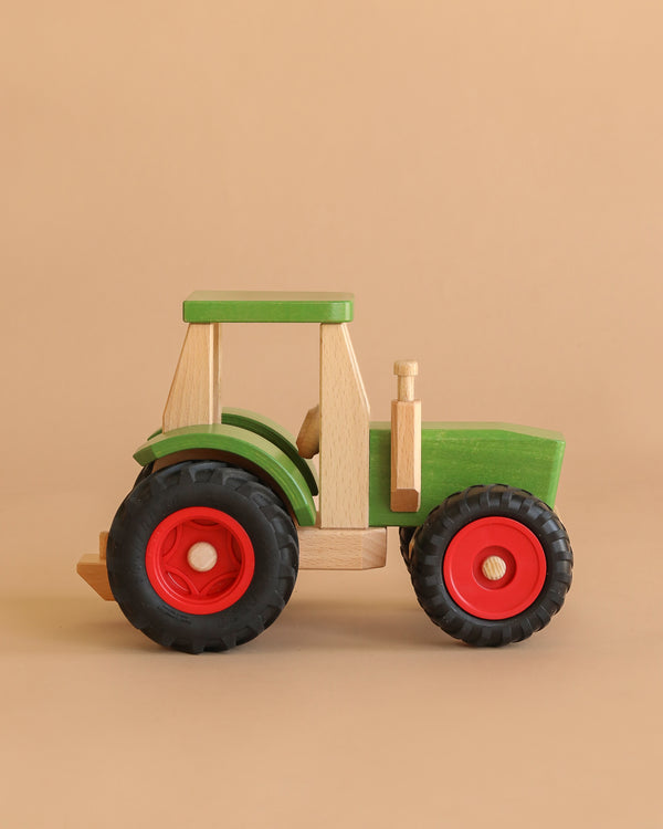 The Fagus Wooden Tractor XXL All Road Limited Edition features a green body with natural wood accents and red and black wheels, shown on a light brown background.