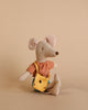 A Maileg Mum Mouse toy sitting against a plain beige background, dressed in striped orange and white Mum mouse clothes and blue shorts, looking adorable and playful.