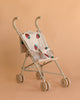 The Konges Sloejd Doll Stroller - Strawberry is a lightweight beige stroller with a padded seat featuring red and teal floral prints, shown against a plain peach background.