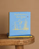 A blue hardcover book, "Winnie-the-Pooh: Pooh Invents a New Game," rests on a wooden surface with gold illustrations—a delightful addition to any collection of classic children's stories or bedtime favorites.
