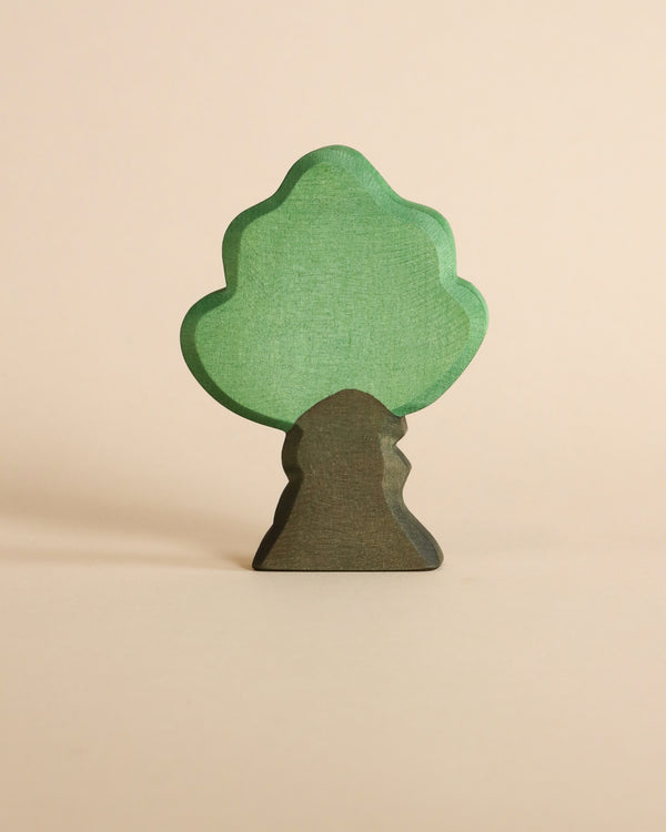 A Ostheimer Oak Tree, designed for imaginative play, with a light green canopy and a dark brown trunk, stands upright against a soft beige background.