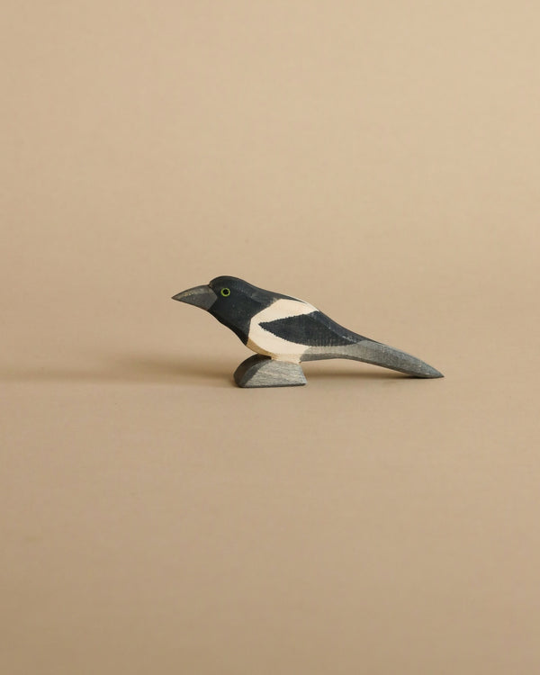 A handcrafted Ostheimer Magpie Bird figurine painted in black, white, and grey, displayed against a plain beige background.