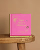 A pink hardcover of "Winnie-the-Pooh: Piglet Meets A Heffalump" sits upright on a wooden stool with another copy flat underneath, against a plain beige background—ideal for fans of classic bedtime stories and Winnie the Pooh.
