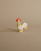 An Ostheimer Rooster - Ochre figurine, painted in white with red and yellow accents, stands against a plain beige background.