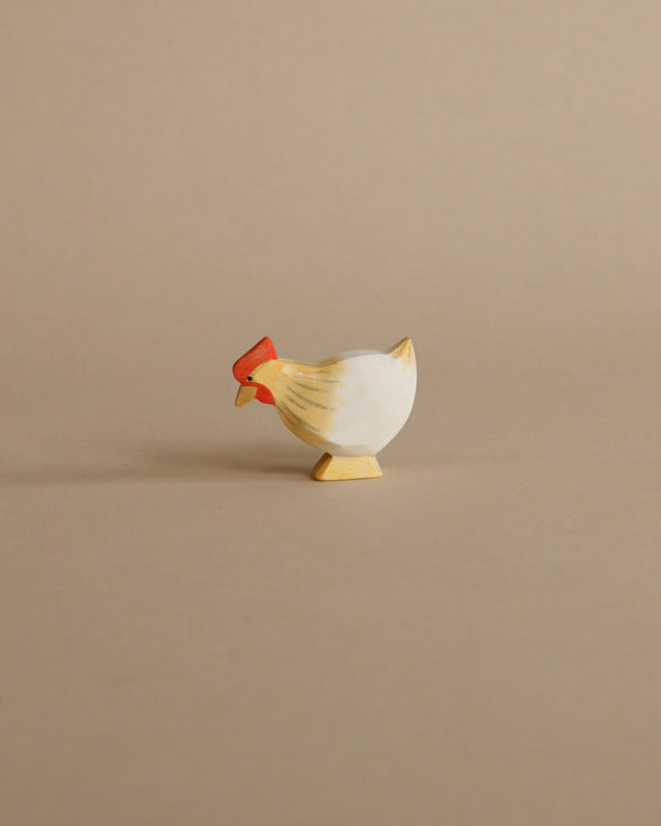 A small handcrafted Ostheimer Hen Standing - Ochre figurine, painted white with red details, standing on a beige background.