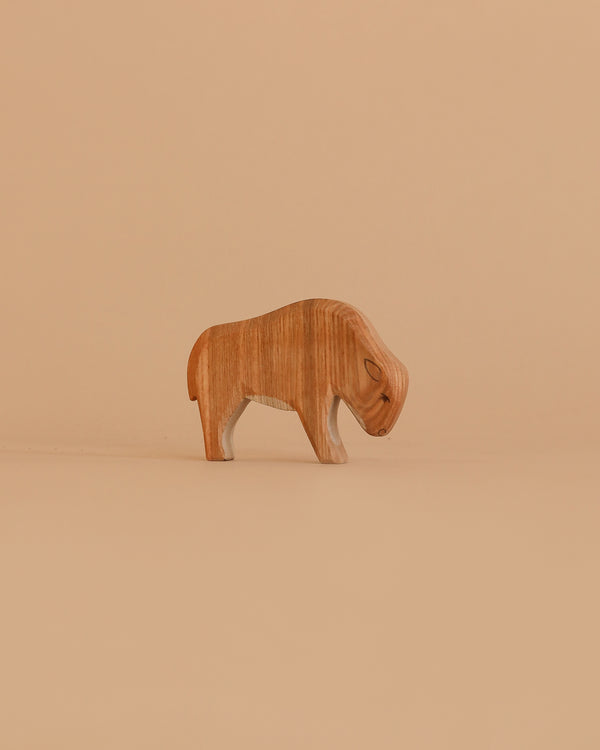 The Ostheimer Bison, Small, is a handcrafted wooden bison with smooth features and minimal detailing, displayed on a plain light brown background—ideal for fans of artisanal toys.