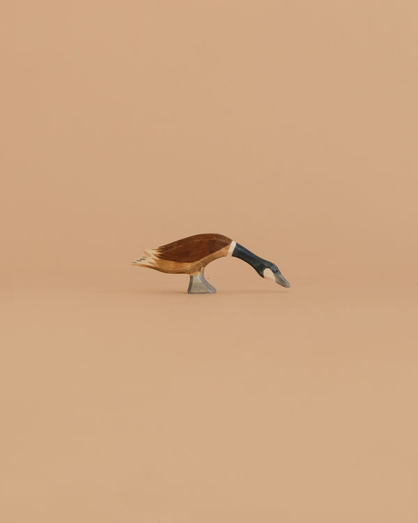The Ostheimer Goose - Canada, Long Neck is a small handcrafted wooden figurine with its head bent down, made from sustainably sourced wood and inspired by classic Ostheimer toy design. Set against a plain light brown background.