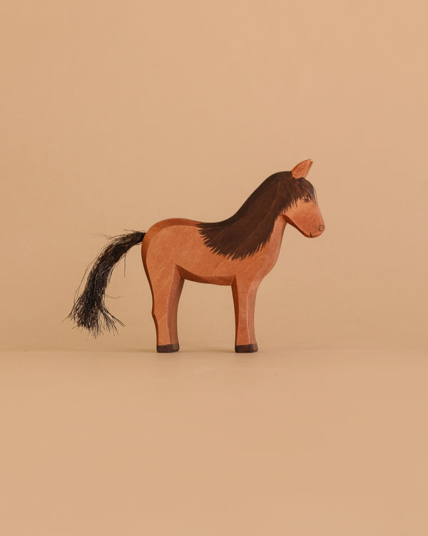 The Ostheimer Horse - Iceland Hrokur is a simple, handcrafted brown wooden toy with a black mane and tail, minimal carved details, and stands facing right on a beige background. Inspired by Ostheimer toys and made in Germany.