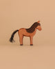 The Ostheimer Horse - Iceland Hrokur is a simple, handcrafted brown wooden toy with a black mane and tail, minimal carved details, and stands facing right on a beige background. Inspired by Ostheimer toys and made in Germany.