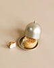 A cinnamon roll with a bite missing sits on a small plate, partially covered by a silver cloche—perfectly sized for the Maileg Grand Dining Room Set or any dollhouse display. A separate piece of the roll rests beside the plate on a beige surface.