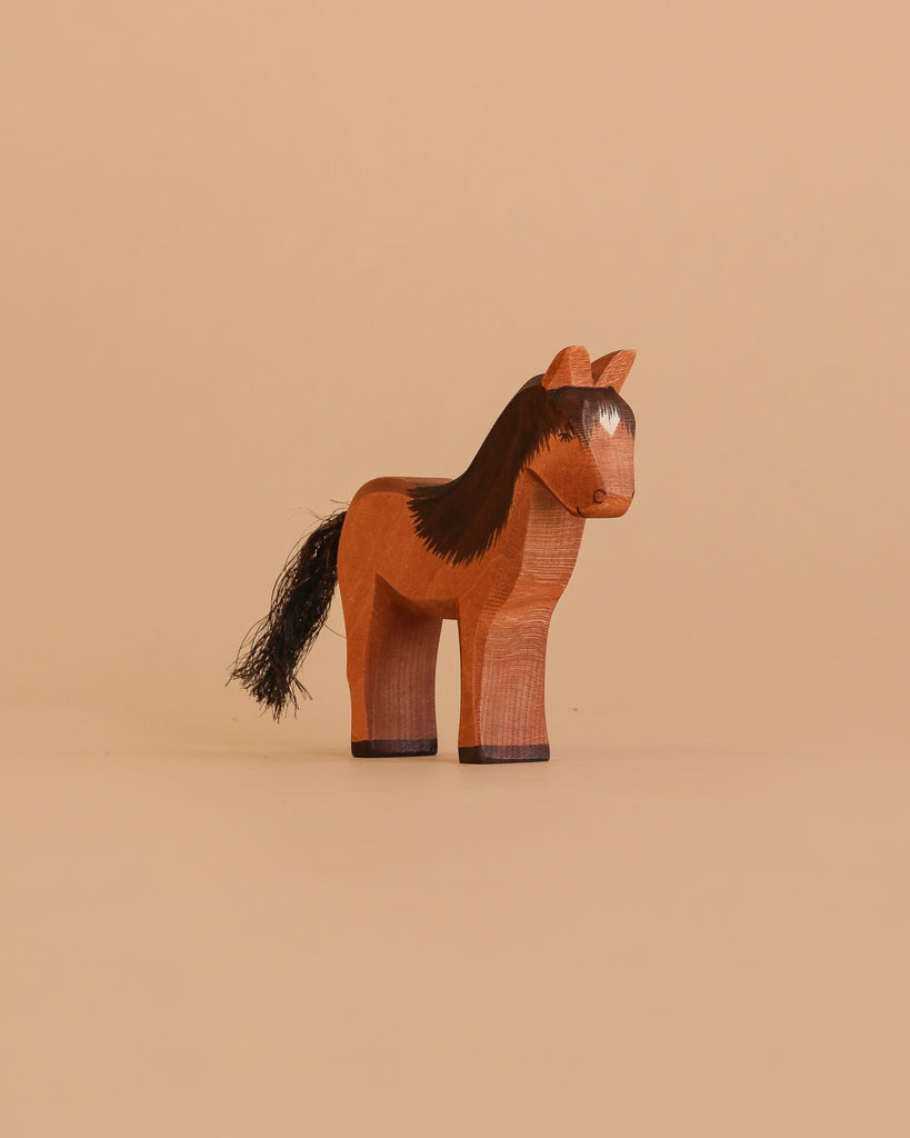 The Ostheimer Horse - Iceland Hrokur is a hand-carved wooden figurine with painted brown and black details and a black tail, standing upright against a plain beige background.