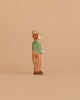 The Ostheimer Young Farmer, a handcrafted wooden figurine in a green shirt, brown pants, and beige hat, stands in profile against a plain beige background.