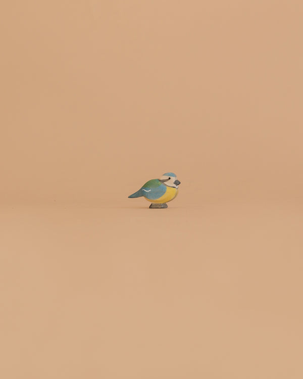 The Ostheimer Bird - Blue Tit is a small wooden figurine with vibrant green, blue, and yellow markings, perfect for imaginative play or as a charming addition to your handcrafted Ostheimer toys collection.