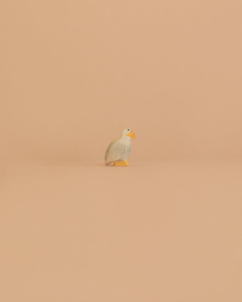 A set of charming Ostheimer Bald Eagle Family figurines, crafted in simple style, stands together against a plain light peach background, capturing the essence of nature with their elegant shapes and hand-painted details.