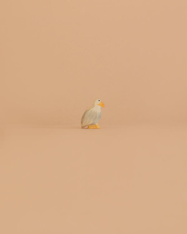 The Ostheimer Bird - Bald Eagle, Small stands alone on a smooth, peach-colored surface with a matching background, capturing the charm of handcrafted toys.