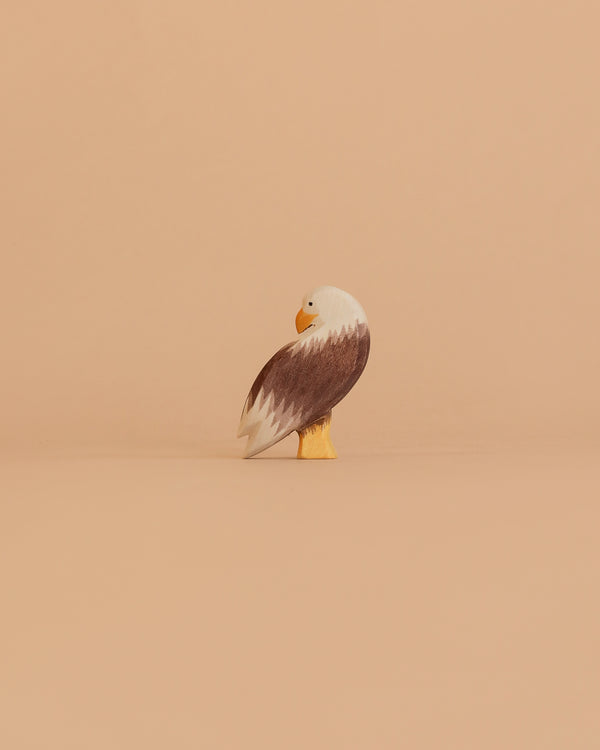 The Ostheimer Bird - Bald Eagle, Standing is a small, handcrafted wooden figurine with brown wings, a white head, and a yellow beak—showcasing the quality of toys Germany is renowned for.