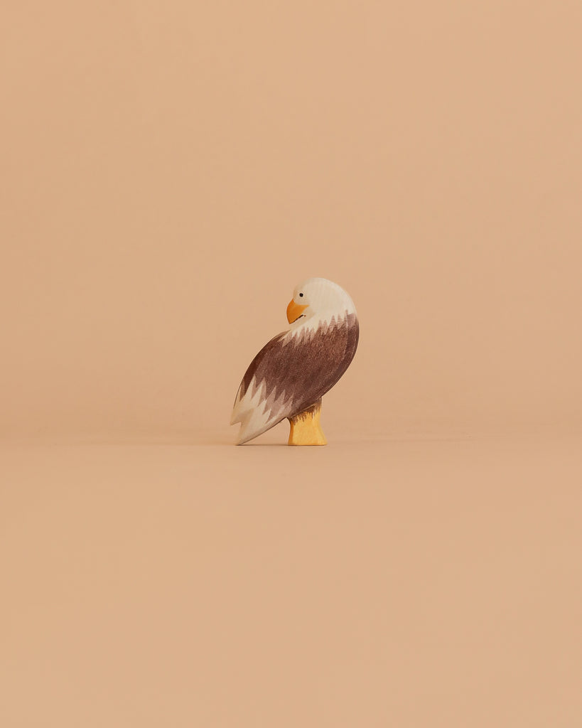 The Ostheimer Bird - Bald Eagle, Standing is a small, handcrafted wooden figurine with brown wings, a white head, and a yellow beak—showcasing the quality of toys Germany is renowned for.
