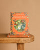 The hardcover "Autumn Story : Jill Barklem" stands upright on a wooden bench with another copy below. Its cover features an illustrated mouse among autumn harvest, berries, and leaves in the magical Brambly Hedge.