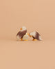 The Ostheimer Bald Eagle Family Set features two large and one small handcrafted figurine, arranged together on a beige surface with a matching background, evoking the charm of classic Ostheimer wooden toys.