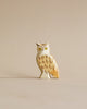 A small Handmade Holzwald Owl figurine, expertly carved with detailed feathers and bright yellow eyes, standing against a plain, light beige background. This piece is part of our collection of high-quality wooden toys.