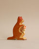 A Handmade Holzwald Kangaroo With Baby sculpture, depicted in an embracing pose, with warm orange and red hues, set against a plain light background. This piece is part of