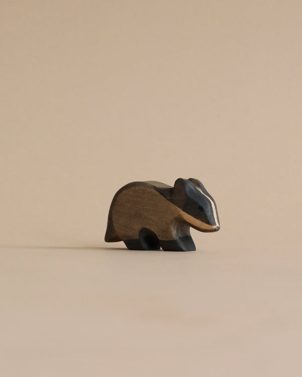 A Handmade Holzwald Badger, presented in a minimalist style, placed against a plain beige background and crafted from materials used in sustainable toys.