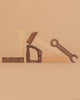 The Wooden Tool Set features a square, hammer, saw, and wrench made of solid rubber wood, artfully arranged upright against a beige background so their shapes spell out “LOVE.”.