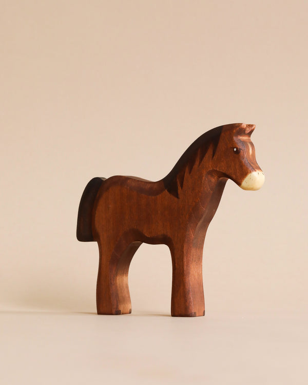 A Handmade Holzwald Dark Brown Horse stands on a plain beige background, featuring a smooth shiny finish treated with high-quality oil and a simple, stylized design.
